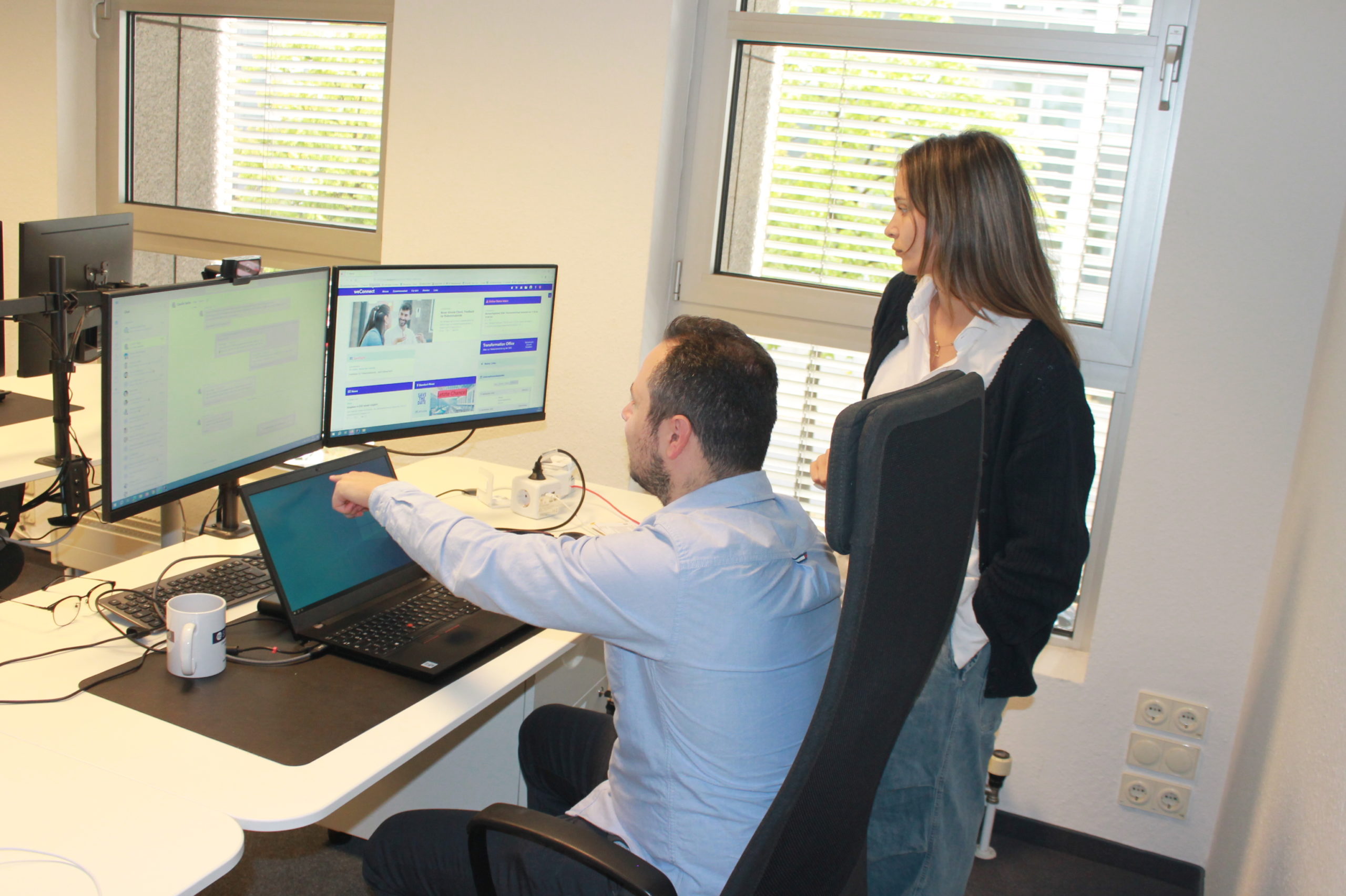 A person showing another person something on a computer screen